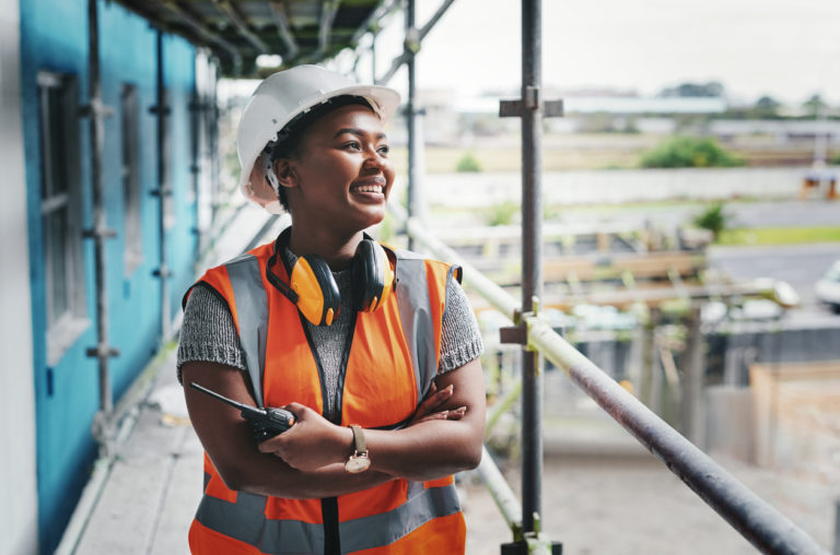 Happy woman on construction site highlights the importance of Careers in Construction Month.